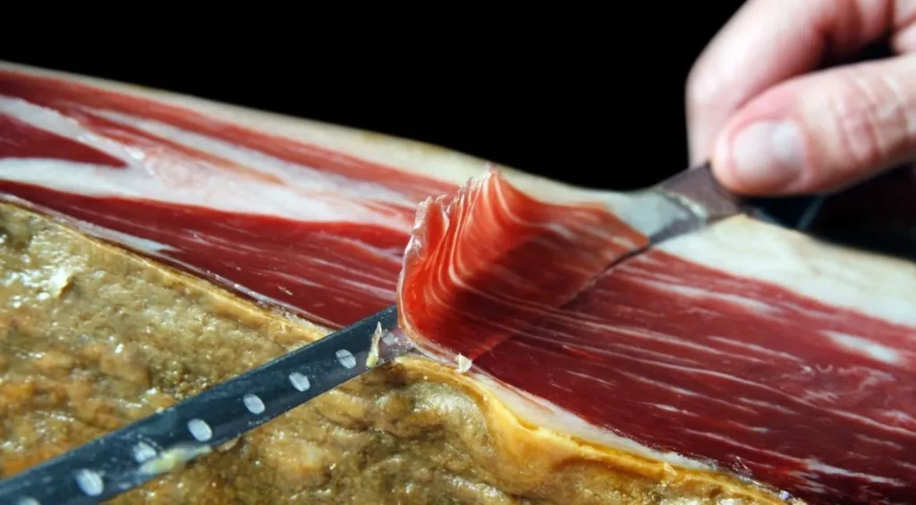 Cuchillo jamonero cortando loncha en jamón ibérico